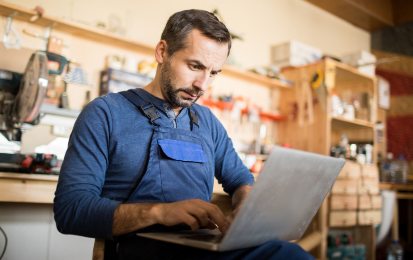 Man in a workshop using a laptop, showcasing the power of an eCommerce site for managing online business operations.